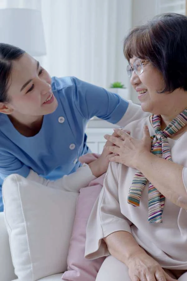 A female caregiver and an elderly woman looking at each other